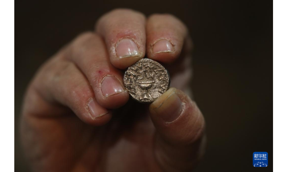 11月23日，以色列文物管理局工作人员展示古银币。以色列文物管理局23日宣布，该国民众在耶路撒冷的一处国家公园发现一枚古银币。这枚银币重约14克，铸造时间距今已有两千年历史。新华社发（穆阿马尔·阿瓦德摄）