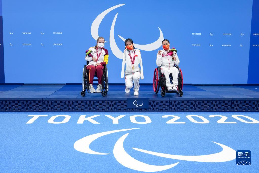 8月27日，在东京残奥会游泳女子50米蝶泳S5级颁奖仪式上，中国选手卢冬（中）单腿下蹲，与队友成姣（右）、西班牙选手玛尔塔·因方特处于同一高度合影。新华社记者 张铖 摄