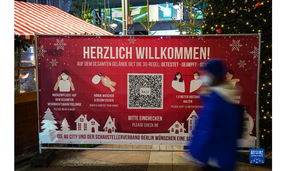 11月22日，在德国首都柏林的布赖特沙伊德广场，一名行人经过圣诞市场旁的防疫须知。

　　受新冠疫情影响，德国柏林、法兰克福等地的圣诞市场有的取消，有的在较为严格的防疫措施下开放。

　　新华社发（斯特凡·蔡茨摄）