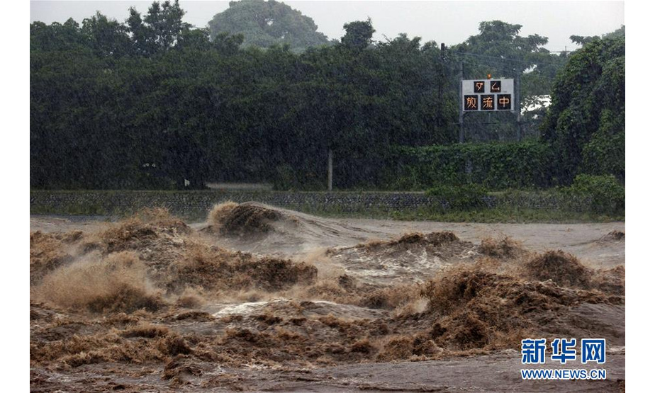 这是7月7日在日本九州地区拍摄的筑后川部分河段，远处的电子屏上显示水库紧急泄洪的通知。 受停滞的梅雨锋面影响，日本九州地区北部7日继续遭遇强降雨天气。迄今，九州因暴雨引发的洪水泛滥、山体滑坡造成的死亡人数升至55人，另有13人失踪。 新华社/共同社
