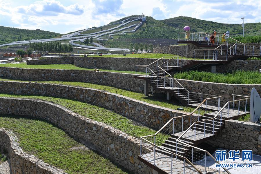 6月30日，游客行走在乌兰浩特市天骏山的栈道上。 天骏山位于内蒙古自治区兴安盟乌兰浩特市郊区，曾因采挖石料而造成山体裸露，植被匮乏，山体上留下了多处深坑。近年来，当地政府加大生态修复力度，为天骏山增添绿色，将荒山改造成旅游景区，吸引游客前往游玩。 新华社发（贝赫 摄）