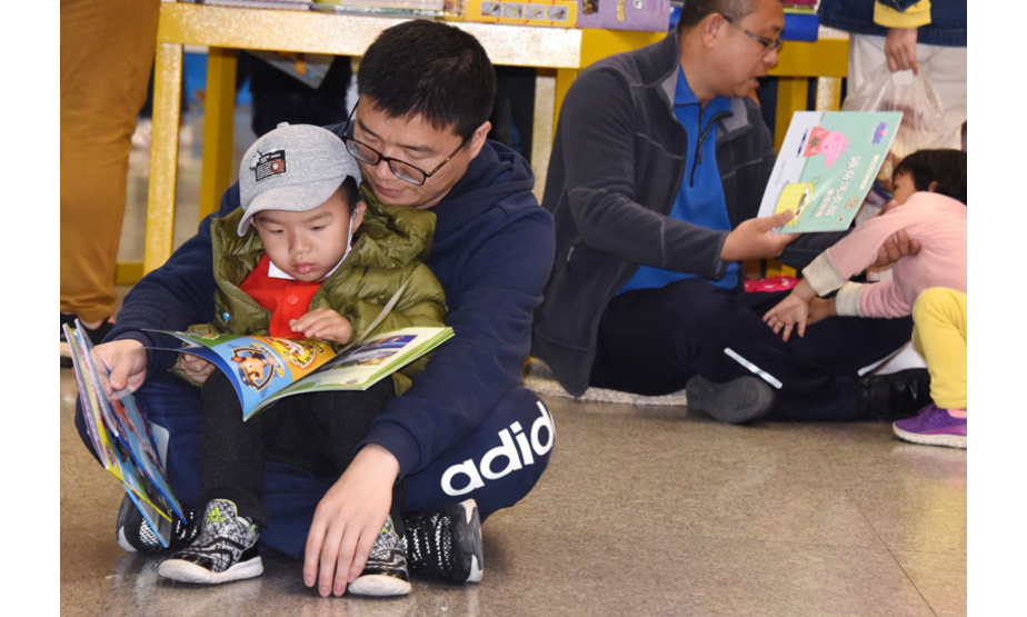4月21日，家长陪着孩子在青岛书城阅读图书。当日，山东青岛举办“牵起爸妈的手”世界读书日享读会，参与者通过“亲子互动阅读”的方式分享亲子阅读的收获和快乐。活动同时向全市家长发出倡议，尽量多抽时间陪伴孩子阅读，言传身教引导子女热爱读书。新华社记者 李紫恒 摄