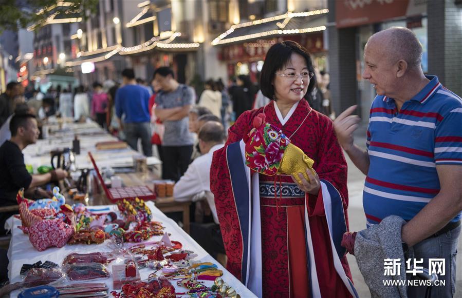 10月20日，身着汉服的游客（右二）在徐州夜市上为外国友人选购工艺品。 新华社记者 陶明 摄 