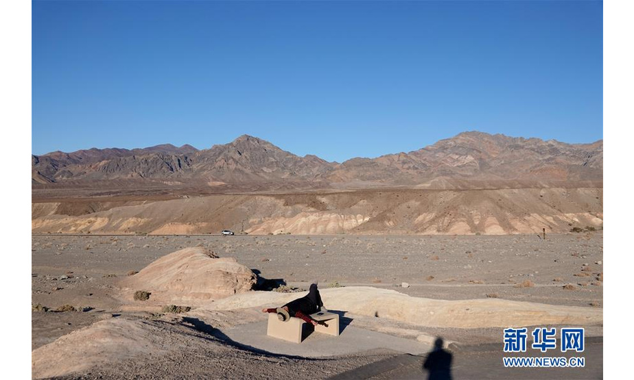 1月11日，一名游客在美国加利福尼亚州死亡谷游览时躺在石凳上休息。 位于美国加州东部的死亡谷属于莫哈韦沙漠的一部分，是美国最大、也是最干旱的国家公园。死亡谷恶水盆地附近的地势低于海平面约86米，为北美洲最低点。 新华社记者 吴晓凌 摄