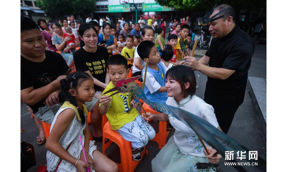 7月21日，“卫家班皮影戏”剧团的艺人们在和睦桥村的文化礼堂前给孩子们演示皮影戏道具。新华社记者 徐昱 摄