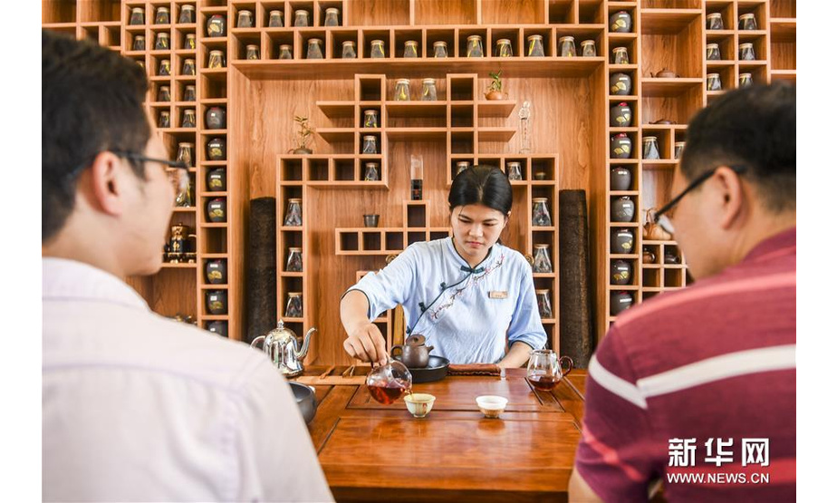 广西梧州市一家茶厂的工作人员在给外来的茶叶采购客商倒茶（7月29日摄）。新华社记者 曹祎铭 摄