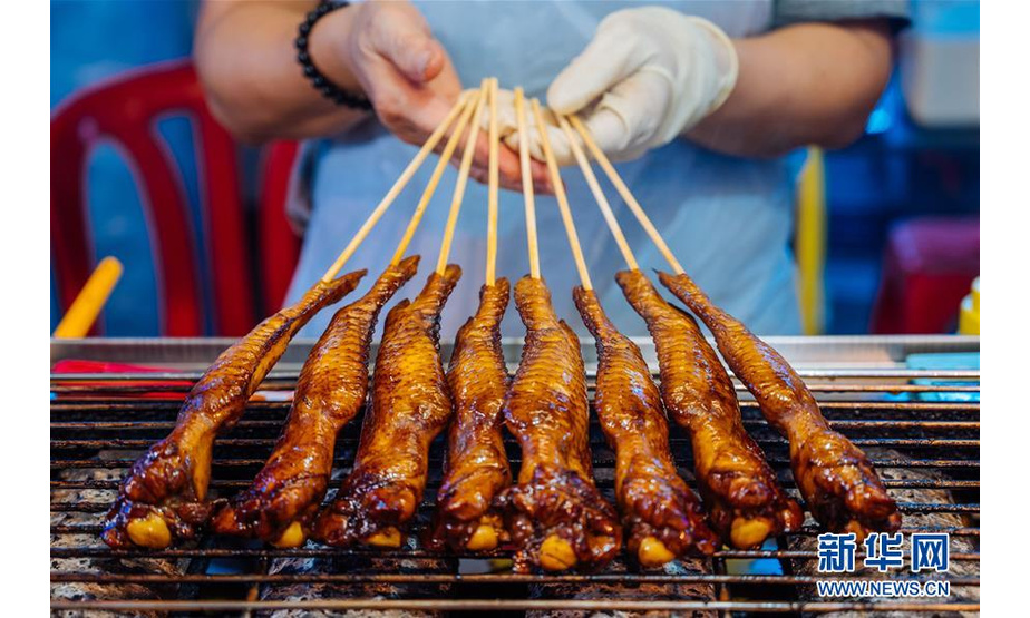 这是2020年9月18日，商户在马来西亚马六甲的鸡场街夜市上制作美食。  新华社记者 朱炜 摄