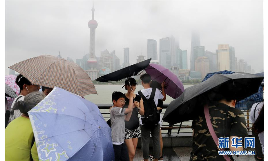 8月17日，在上海外滩，一名小朋友的雨伞在大风中被吹变形。新华社记者 方喆 摄