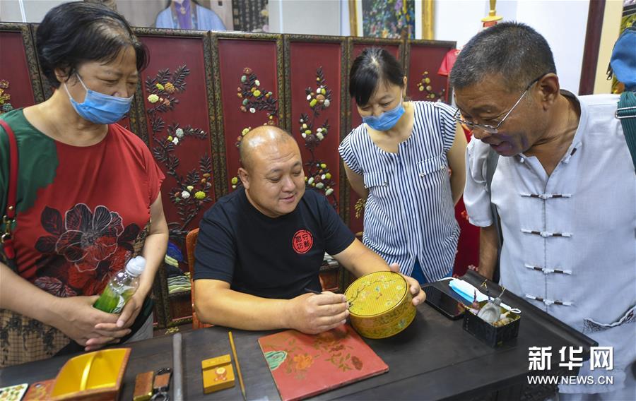 7月4日，省级非遗传承人缑建辉（左二）在廊坊市群艺馆展示雕漆工艺品。新华社记者 李晓果 摄