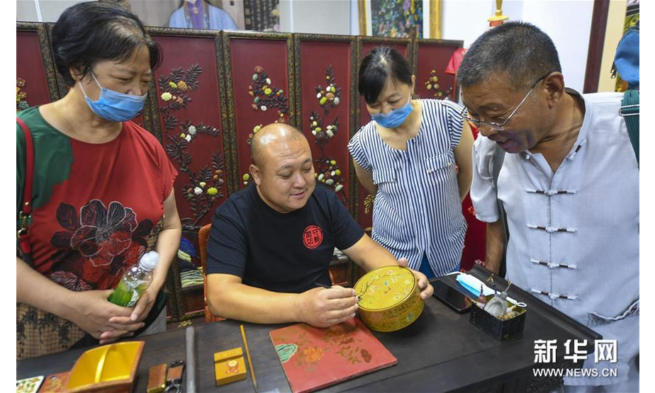 7月4日，省级非遗传承人缑建辉（左二）在廊坊市群艺馆展示雕漆工艺品。新华社记者 李晓果 摄