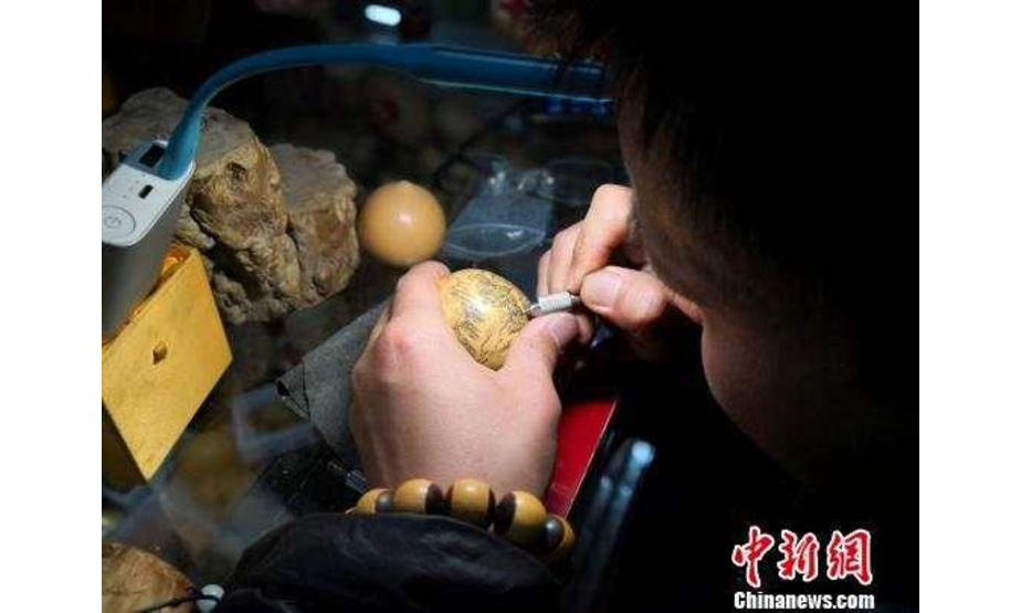近日，甘肃“80后”艺人赵华荣在他的刻葫芦摊位上雕刻一只未完成的微雕葫芦。图为赵华荣在雕刻葫芦。杨娜　摄