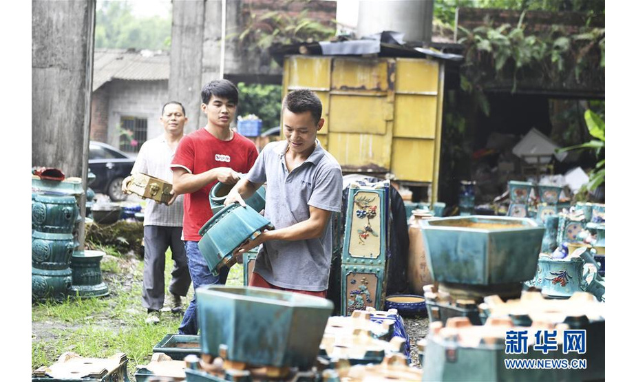 赵勇（右）在自己创办的陶瓷制品加工厂与工人一起搬运制作完成的花瓶（8月11日摄）。  新华社记者 曹祎铭 摄