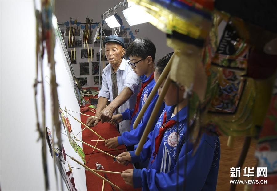 近年来，位于河北省唐山市丰润区李钊庄镇的大漫港小学将剪纸、皮影等传统技艺引进校园，通过开设传统技艺表演课程、聘请民间艺人等方式，让学生感受传统技艺的魅力。图为6月13日，民间艺人在大漫港小学辅导学生表演皮影戏。 新华社发（刘满仓 摄）