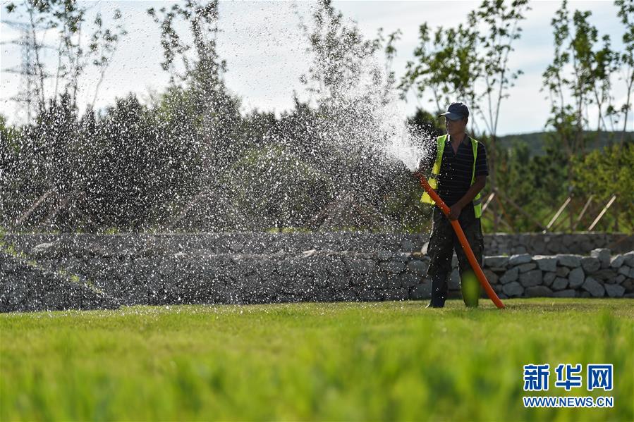 6月30日，工人在乌兰浩特市天骏山的草坪上浇水。 天骏山位于内蒙古自治区兴安盟乌兰浩特市郊区，曾因采挖石料而造成山体裸露，植被匮乏，山体上留下了多处深坑。近年来，当地政府加大生态修复力度，为天骏山增添绿色，将荒山改造成旅游景区，吸引游客前往游玩。 新华社记者 刘磊 摄