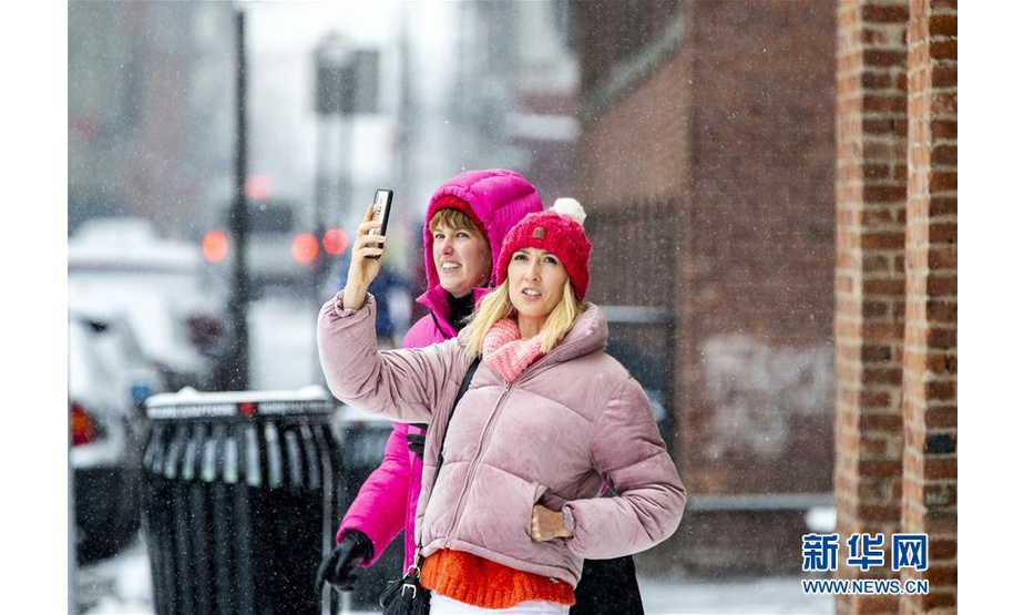 2月20日，在美国纽约布鲁克林大桥附近的商业区，游客在雪中拍照。

　　当日，纽约迎来降雪天气。

　　新华社记者 王迎 摄