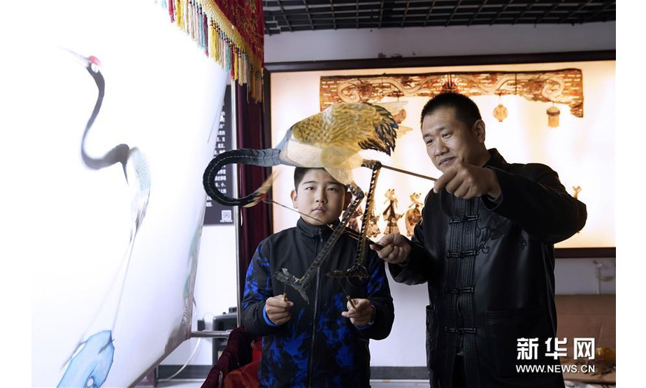 11月10日，郭宝（右）在皮影传承馆内教孩子皮影。新华社记者金良快摄