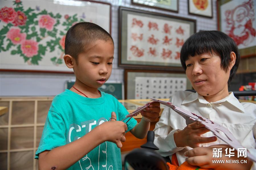 6月29日，华丽指导儿子创作剪纸作品。新华社记者 张楠 摄