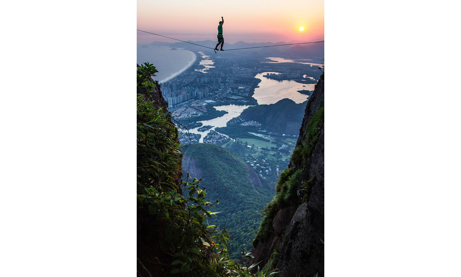 摄影师拉斐尔•莫拉(Rafael Moura)喜欢周游世界，拍摄世界各地的壮阔美景。他在里约热内卢游玩时，和一名朋友攀爬了当地著名的上桅帆岩，偶然的机会，他拍下了让人惊叹的照片——在上桅帆岩两座山头之间，几名高空走绳者在82英尺(约24米)长的绳索上小心翼翼地行走，他们的脚下便是几百米的高空，身后是缓缓升起的太阳，在朝晖、高山、流水的映衬下，他们的身影显得更加宏伟。