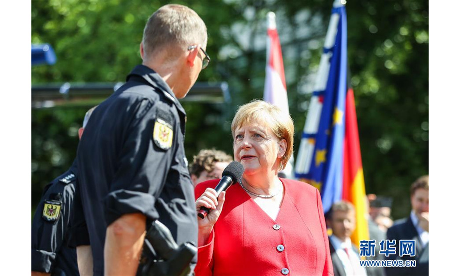 8月18日，在德国首都柏林，德国总理默克尔（右）与一名警察交流。德国联邦政府8月17日至18日举办开放日活动，包括总理府在内的多个政府部门对公众开放，通过多种活动向民众介绍各自的历史、现状及职能。新华社记者 单宇琦 摄