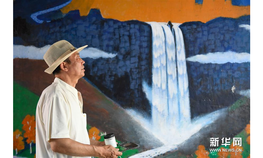 7月18日，吴吉人从自己作画的墙壁前走过。72岁的吴吉人是吉林省吉林市船营区北极街道致和南社区的居民。曾从事美术工作的他，退休后仍每天坚持在家练习画画。2015年末，社区开始整治墙壁上的野广告，吴吉人主动担任志愿者，刷掉影响美观的广告，画上了自己创作的墙壁画。如今，他已创作10多幅墙壁画，共百余平方米。“我想用我的画让城市变得更美丽。”吴吉人说。新华社发（颜麟蕴摄）