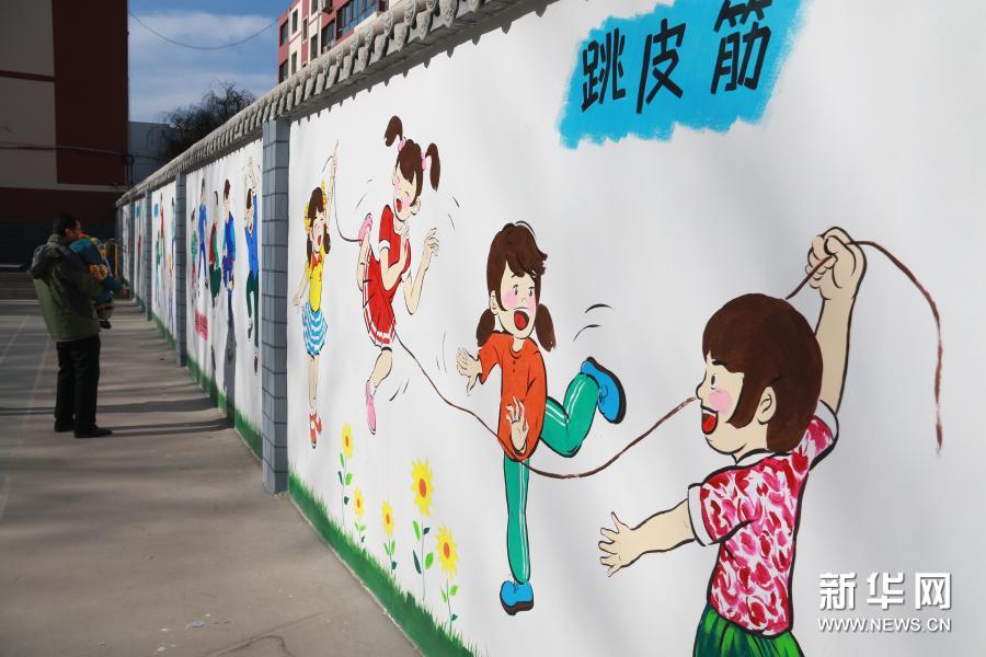 近日，甘肃省敦煌市沙州镇南街社区的一处特色文化墙亮相，墙面上用卡通画描绘了滚铁环、跳皮筋、打沙包等具有时代特征的儿童游戏场景，唤起人们美好的童年回忆。图为12月5日，市民在敦煌市沙州镇南街社区观看文化墙。新华社发（张晓亮 摄）