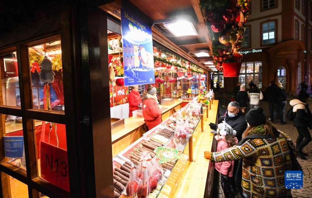 11月22日，人们在德国法兰克福圣诞市场的一家甜点摊铺前驻足。

　　受新冠疫情影响，德国柏林、法兰克福等地的圣诞市场有的取消，有的在较为严格的防疫措施下开放。

　　新华社记者 逯阳 摄