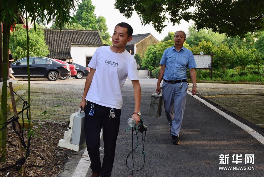 6月30日，朱生荣（右）和儿子朱强（左）携带放映设备来到马鸣村将军湖广场。新华社记者 郑梦雨 摄