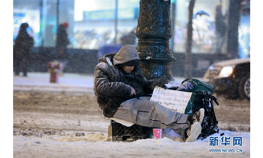 1月17日，在美国芝加哥，一名无家可归者坐在街头。 美国芝加哥当日遭暴风雪袭击，地面积雪严重，影响交通和出行。 新华社记者 汪平 摄