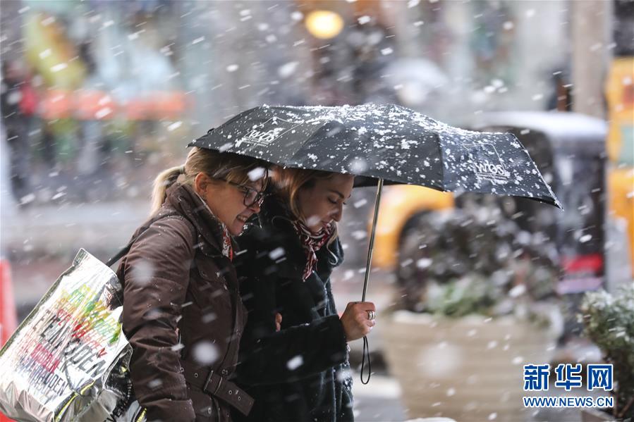 12月2日，行人冒雪走在美国纽约时报广场上。 当天，纽约遭遇雨雪天气，给人们出行带来不便。 新华社记者 王迎 摄