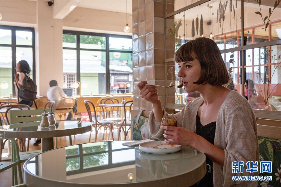 9月10日，在南非约翰内斯堡一家甜品店内，顾客正在品尝牛奶蛋挞。新华社发（耶希尔摄）