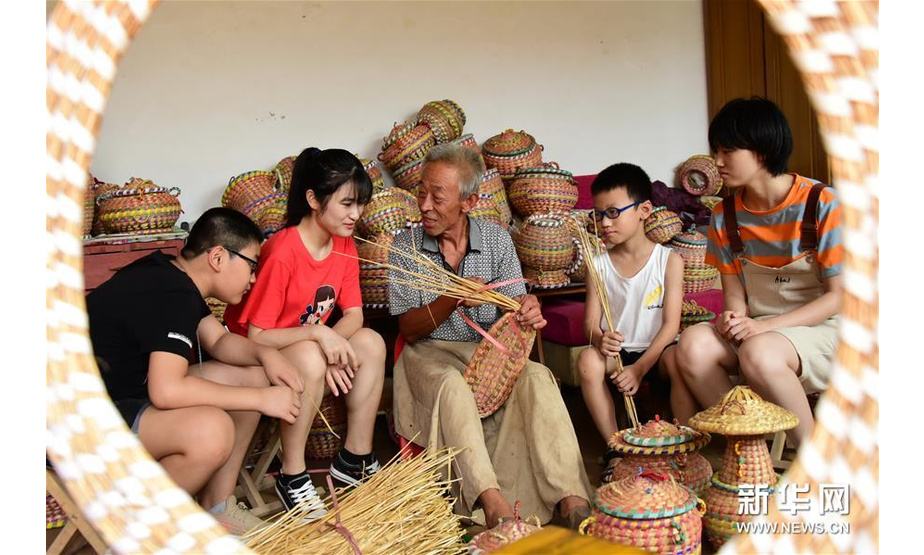 8月2日，杨振国在家中向小朋友介绍草编技艺。新华社记者 朱旭东 摄