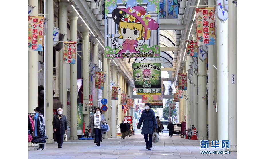 1月13日，在日本岐阜县岐阜市，佩戴口罩的行人走在一条商业街上。 新华社/共同社