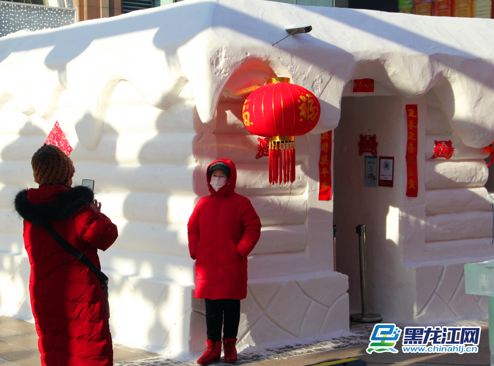 游人在非遗雪屋前拍照留念