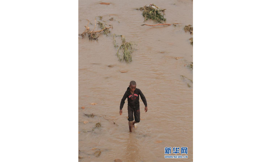 3月17日，在津巴布韦马尼卡兰省的奇马尼马尼，一名男孩行走在涨水的河中。 津巴布韦政府16日表示，15日晚开始袭击该国东部的强热带气旋“伊代”造成的死亡人数升至31人，另有数十人失踪。 新华社发（肖恩·朱萨摄）