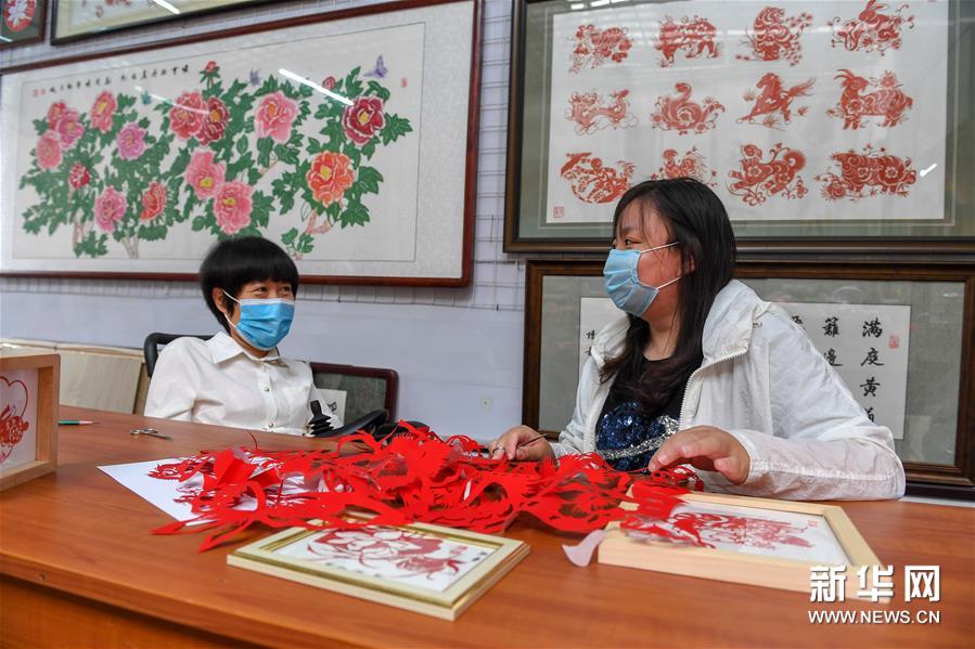 6月29日，华丽（左）指导学员王聪进行剪纸创作。新华社记者 张楠 摄
