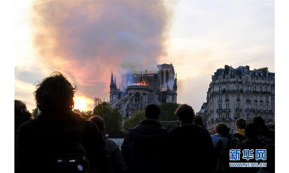4月15日，在法国巴黎，人们围观着火的巴黎圣母院。 新华社发（亚历山大·卡曼摄）