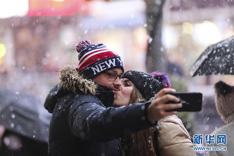 12月2日，一对情侣在美国纽约时报广场上自拍。 当天，纽约遭遇雨雪天气，给人们出行带来不便。 新华社记者 王迎 摄