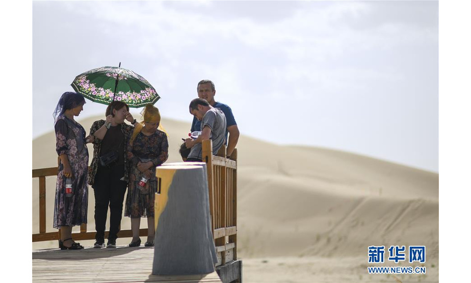 游人在罗布人村寨游览（6月19日摄）。 入夏以来，新疆尉犁县罗布人村寨景区迎来旅游旺季。根据景区提供的数据，自“五一”小长假至6月23日，罗布人村寨接待游客5.2万多人次，相比去年同期增长约78%。 新华社记者 赵戈 摄