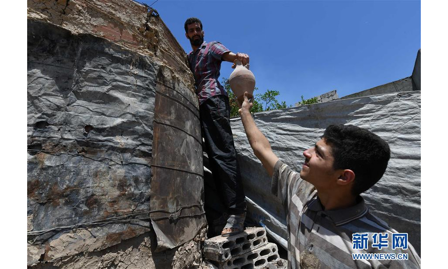 6月5日，在叙利亚霍姆斯，扎卡莱亚·卡尔库什（左）与儿子在作坊外工作。  新华社发（阿马尔摄）