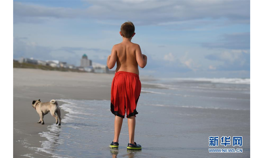 9月12日，在美国北卡罗来纳州威尔明顿市，一个男孩与小狗在海滩玩耍。 新华社记者 刘杰 摄 