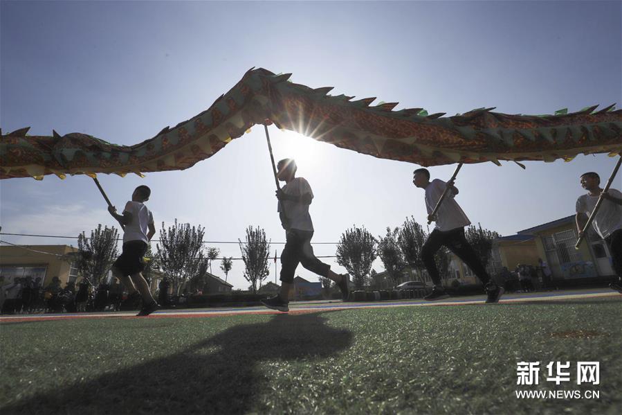 8月4日，孩子们在河北省遵化市平安城镇大麻各庄村校园操场练习民俗节目。暑假期间，河北唐山遵化市平安城镇大麻各庄村的孩子们在民间艺人的指导下学习舞龙、赶驴、跑旱船等民俗节目，丰富暑期生活。新华社发（刘满仓 摄）