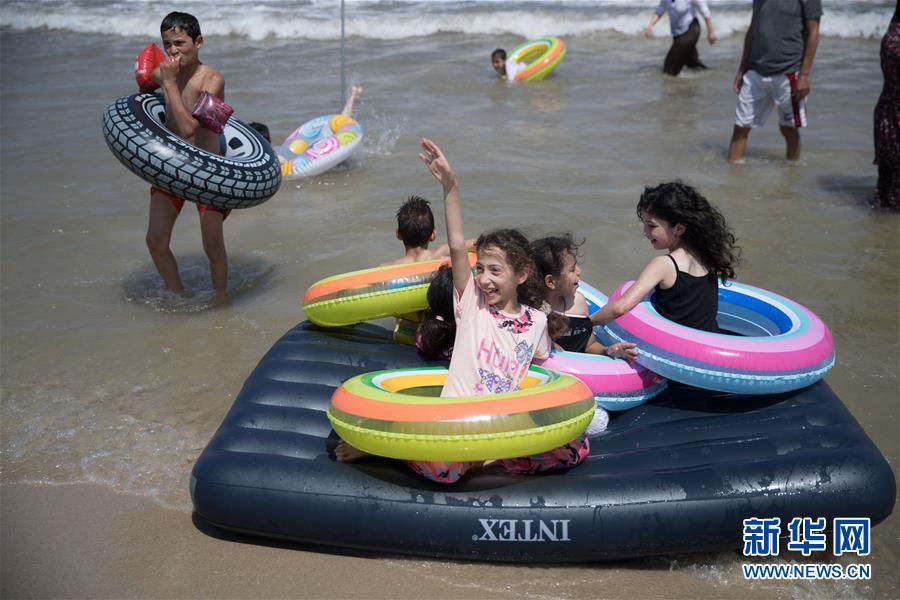 7月8日，在以色列特拉维夫，巴勒斯坦儿童在海边戏水。 7月12日是今年“三伏”中“初伏”的第一天，这意味着高温高湿的“桑拿天”将逐渐成为天气“主角”，我国大部分地区开启“蒸煮模式”或“烧烤模式”。 而近日北半球多地也处在高温酷暑中。 新华社记者 郭昱 摄