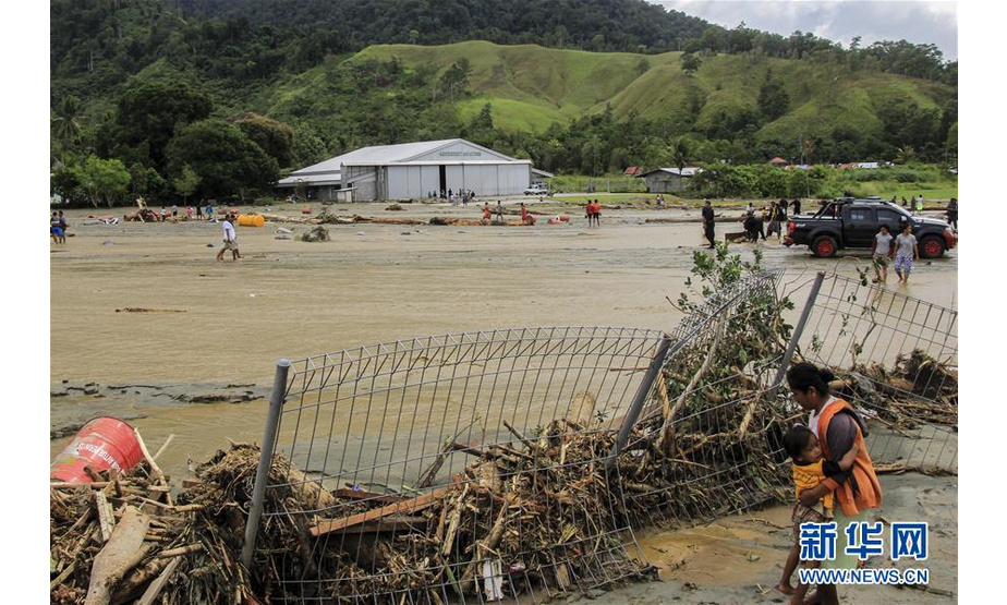 3月17日，在印度尼西亚巴布亚省森塔尼，一名妇女抱着孩子站在被洪水冲垮的围栏旁。印度尼西亚抗灾署17日说，印尼东部巴布亚省16日晚发生的洪涝灾害已导致42人死亡、21人受伤。新华社发