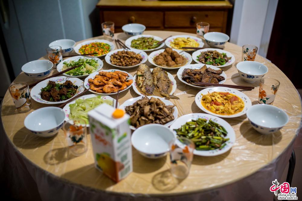 满满一桌的年夜饭做好了，妈妈脸上的汗珠和笑容都清晰地被我记在脑子里，这一刻，自己仿佛回到了许多年前，那时候自己才比餐桌高不了多少，那时候看着一桌的美味，总是忍不住想去偷吃，那时候，妈妈总会拉着我的手。中国网记者 郑亮 摄