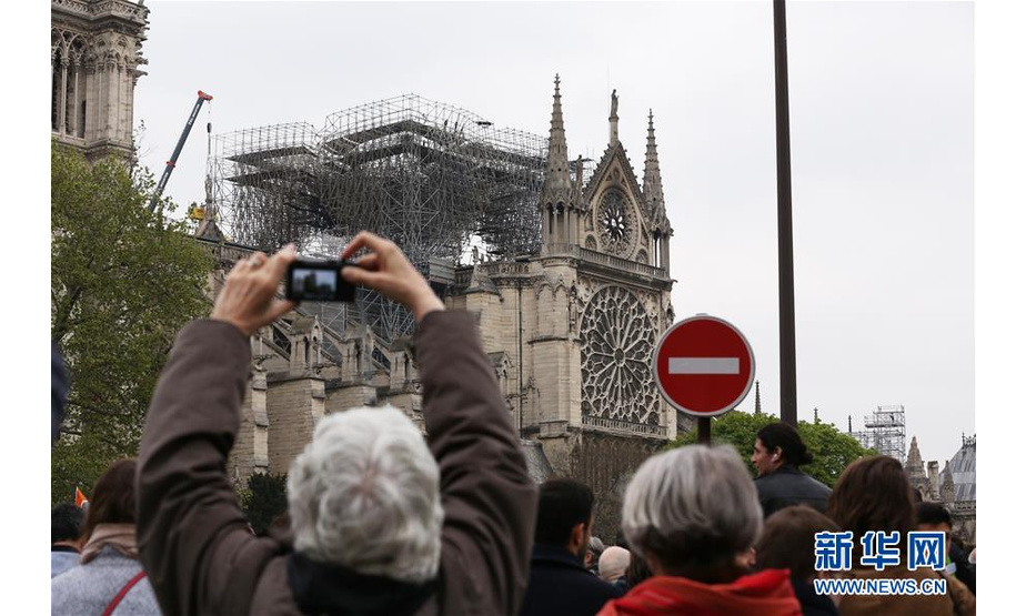 　4月16日，在法国巴黎，人们带着鲜花前来看望“受伤”的巴黎圣母院。新华社记者 高静 摄