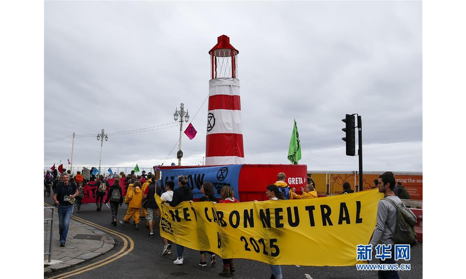 9月22日，在英国布莱顿，人们手持标语参加气候变化游行。 当日，民众在英国布莱顿举行游行活动，呼吁社会各界应对气候变化。 新华社记者韩岩摄