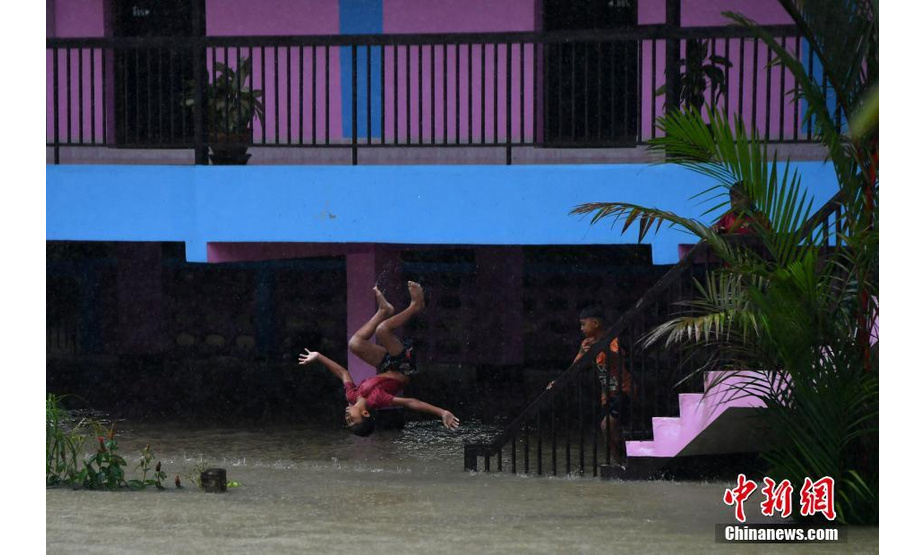 当地时间2月27日，泰国南部那拉提瓦省，当地遭遇暴雨和洪水灾害，水位猛涨，部分街道被淹。图为一名儿童在水中玩耍。