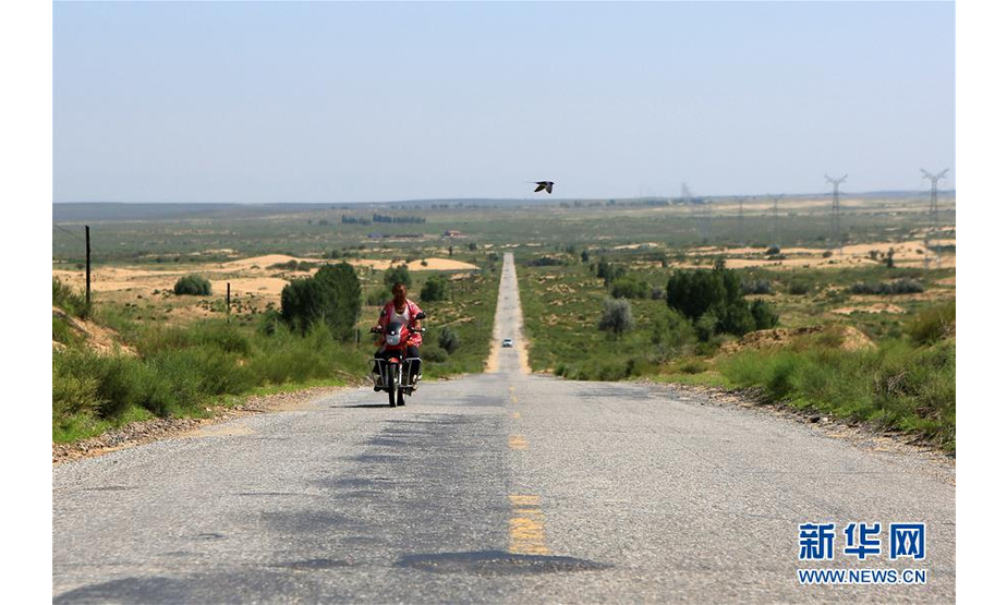 在内蒙古鄂尔多斯市杭锦旗，一名村民骑摩托车行驶在锡乌公路上（7月26日摄）。 新华社记者 卢烨 摄