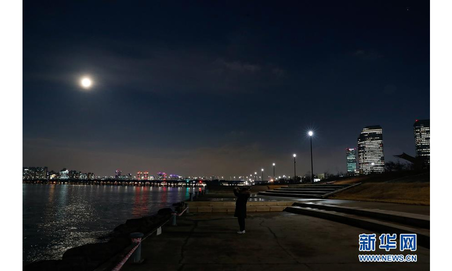 2月19日，一名游客在韩国首尔汝矣岛汉江公园拍摄月亮。

　　年度“最大最圆月”19日（正月十五）现身天宇“合体”元宵月，为人们在世界各地赏月平添情趣。

　　新华社记者 王婧嫱 摄