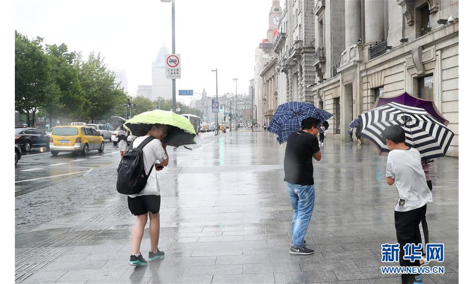 8月17日，几位游客手持雨伞顶风走在上海中山东一路街道上。新华社记者 方喆 摄